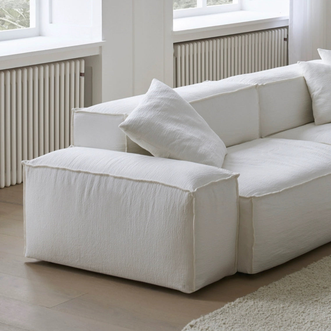 Whisper Breathable Cotton Sofa 2 seater armrest close-up showing soft white breathable cotton muslin fabric and plush cushions in a bright modern living room