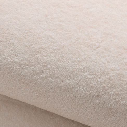 Close-up of the Woven Whisper Rug showing its plush beige texture and soft, velvety pile.
