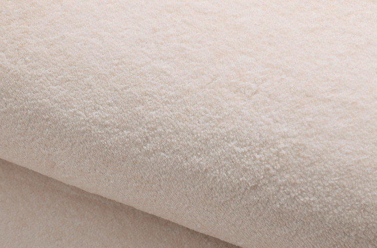 Close-up of the Woven Whisper Rug showing its plush beige texture and soft, velvety pile.