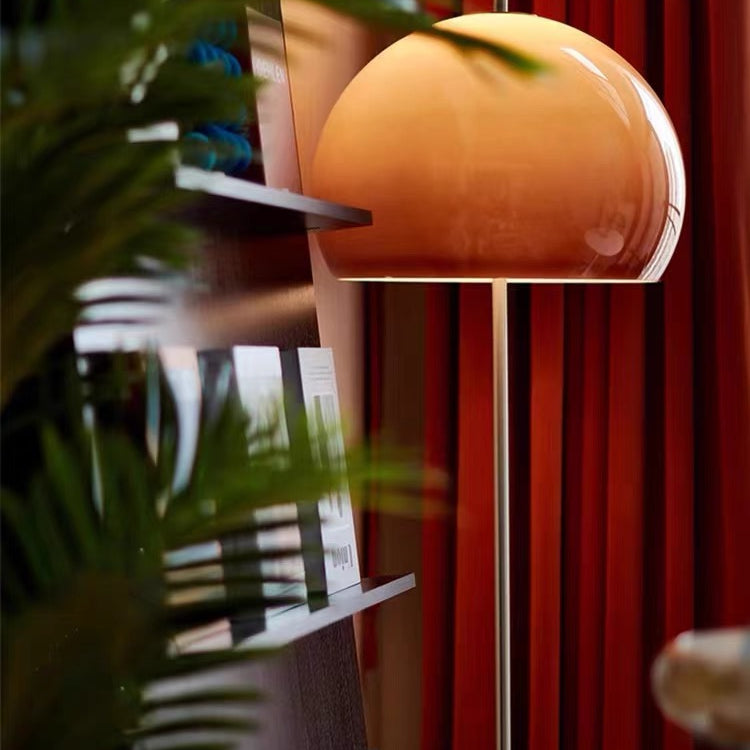 Yellow Dome Glass Standing Floor Lamp glowing beside bookshelf and red curtains with soft warm ambiance