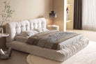 Italian-style cloud bed in ivory suede fabric, displayed in a beige modern bedroom with a carpet under it.