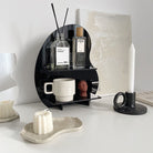Acrylic Desktop Organizer in black, holding perfumes and a mug on a modern white vanity setup