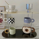 Acrylic Three-Tier Desktop Organizer showcasing colorful mugs and glassware on a marble tabletop