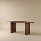 Adrian solid wood dining table with fluted legs and oval top on beige studio background