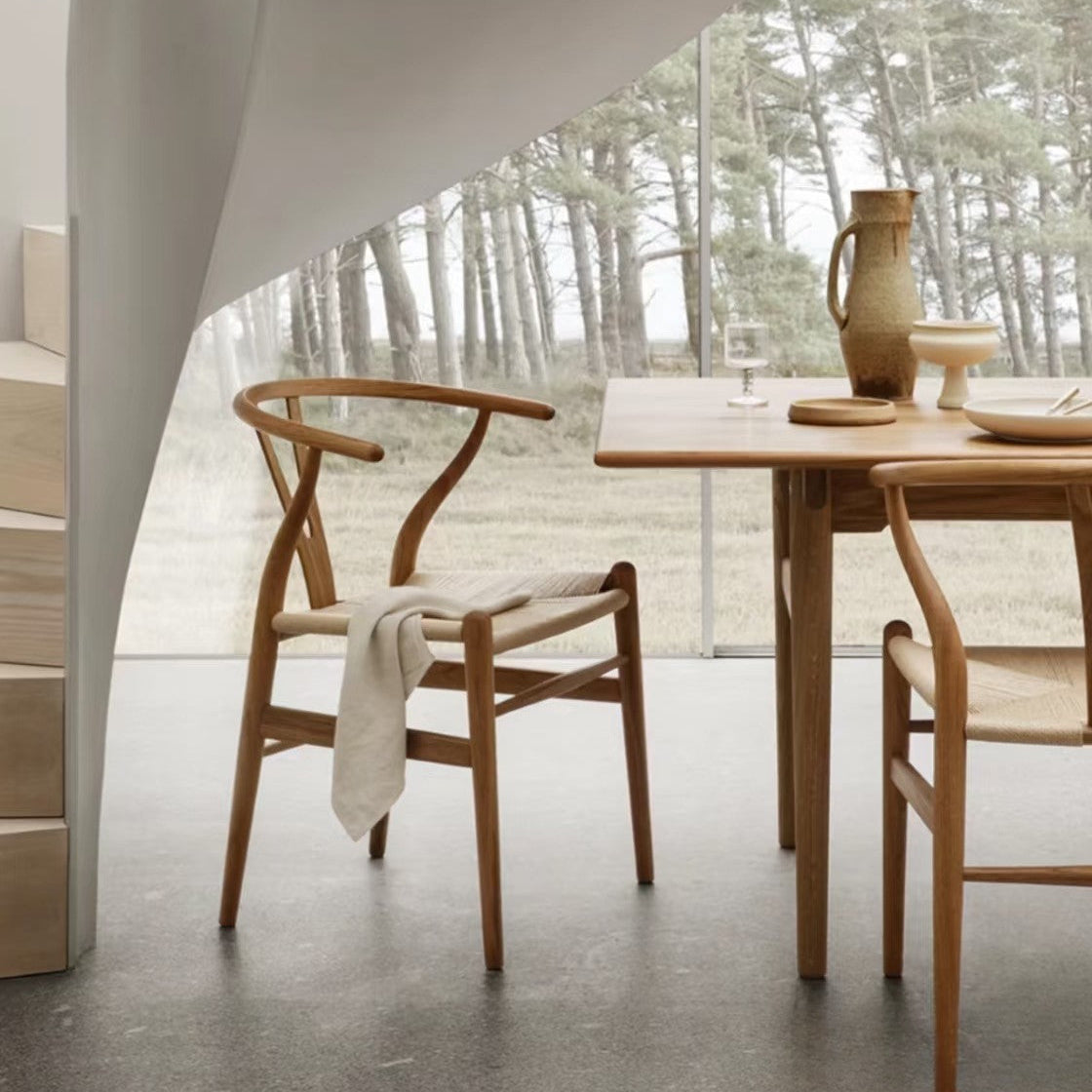 Alden Wishbone Dining Chair in a natural wood finish, styled in a minimalist dining room with a woven seat and soft neutral décor