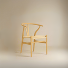 Alden Wishbone Dining Chair with a natural wood frame and woven seat, shown in a soft neutral studio setting.