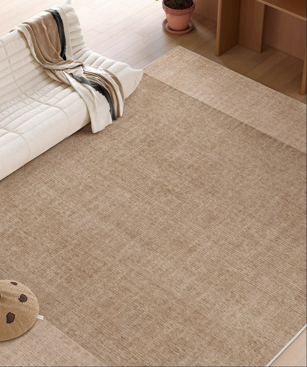 Close-up view of the Alpine Luxe Rug in warm beige, showing its soft texture beside a white sofa and wooden flooring.