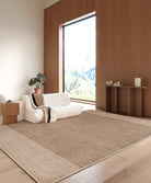 A modern living room featuring the Alpine Luxe Rug in warm beige tones, styled with a low white sofa and large picture window