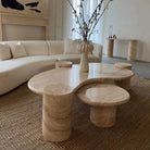 Ardea Travertine Coffee Table Set with layered stone surfaces and cylindrical bases styled beside a curved cream sofa