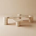 Ardea Travertine Coffee Table Set featuring sculptural cylinder legs and curved stone tops in a minimalist beige studio setting