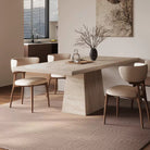 Angled view of Ardella sintered stone dining table with trapezoid base and beige chairs in warm minimalist dining space