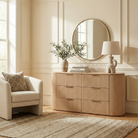 Arden fluted oak dresser styled in a bright modern entryway with a round mirror, table lamp, and olive branches.
