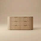 Arden oak dresser featuring a curved silhouette with vertical fluted wood texture and six spacious drawers with brass finger pulls.