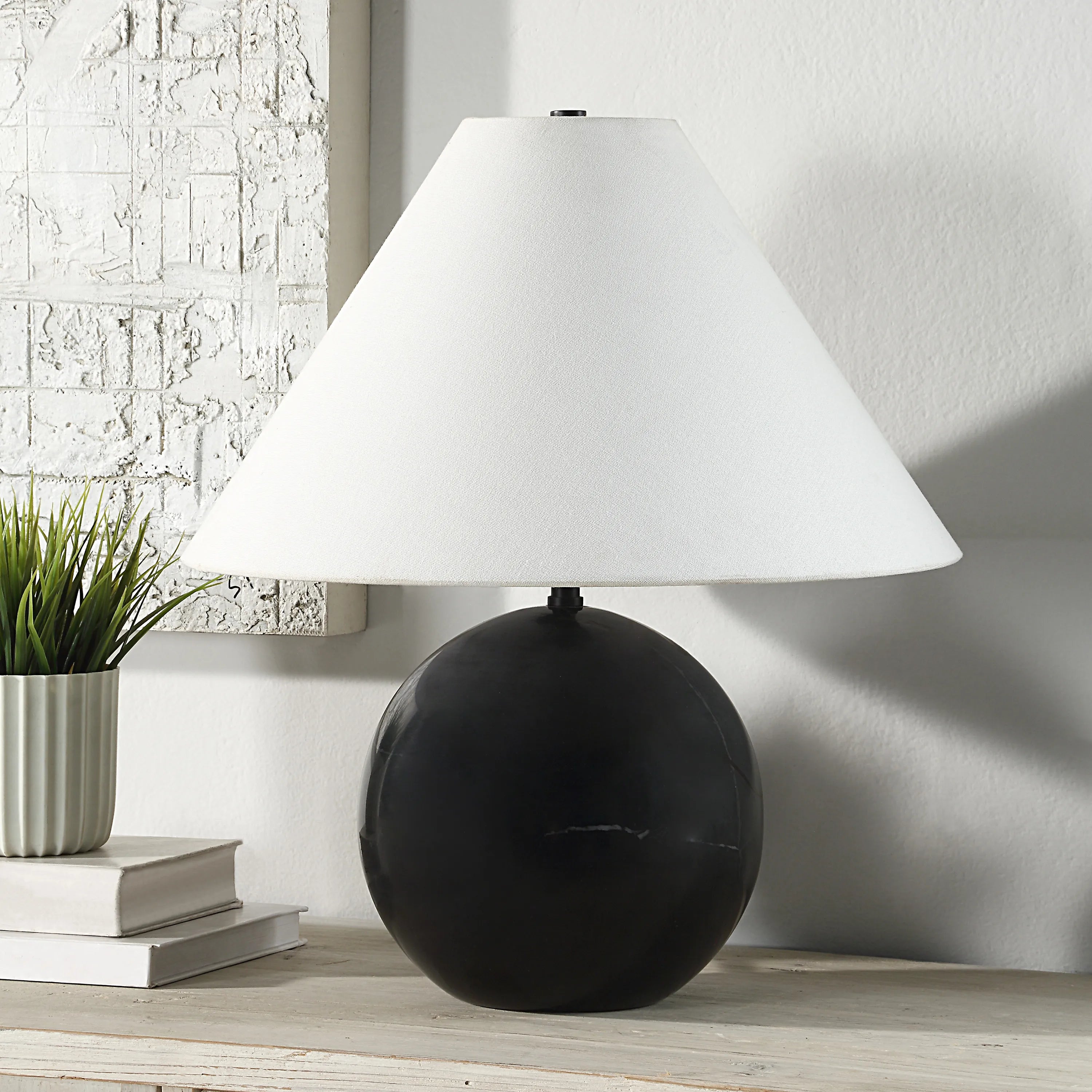 Arlo Black Marble Sphere Table Lamp with white shade on wooden table beside books and plant in bright modern room