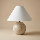 Table lamp with a stone-like base and white shade on a beige background