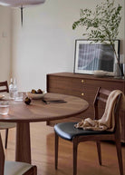 Aspen Classic Dining Chair with walnut frame and black seat cushion styled beside a round wood dining table