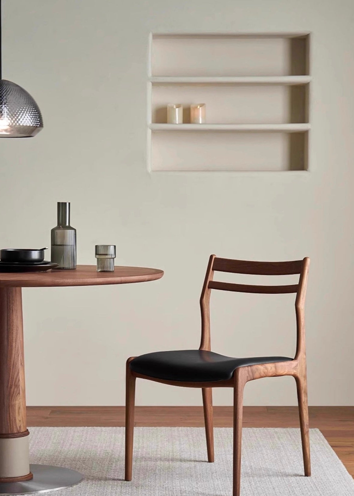 Aspen Classic Dining Chair with walnut frame and black cushioned seat shown beside a round wooden dining table