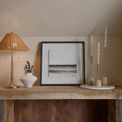 Aurelia Candle Holders displayed on a rustic wood mantel beside a rattan lamp, ceramic vase, and framed artwork