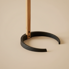 Detail view of the Bianca floor lamp's sturdy black metal horseshoe base supporting the light oak wood stem.