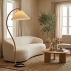 Bianca curved wood floor lamp styled in a minimalist living room with a cream boucle sofa and olive tree, highlighting its warm ambient lighting.