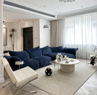 Blooming Embrace Modular Sofa in navy blue fabric styled in a modern living room with white walls, marble coffee table, and soft lighting