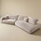 Budapest Lounger in light beige ultra suede fabric with deep cushions and wide armrest on a warm beige studio background