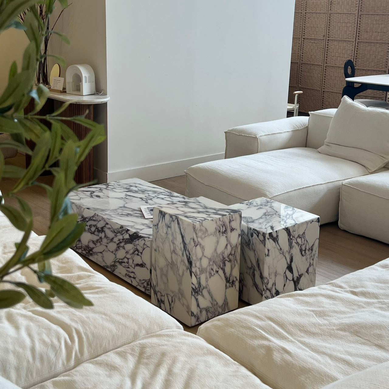 Bulgari Charm Coffee Table in white marble with gray veining styled in modern living room with cream modular sofa and wood flooring