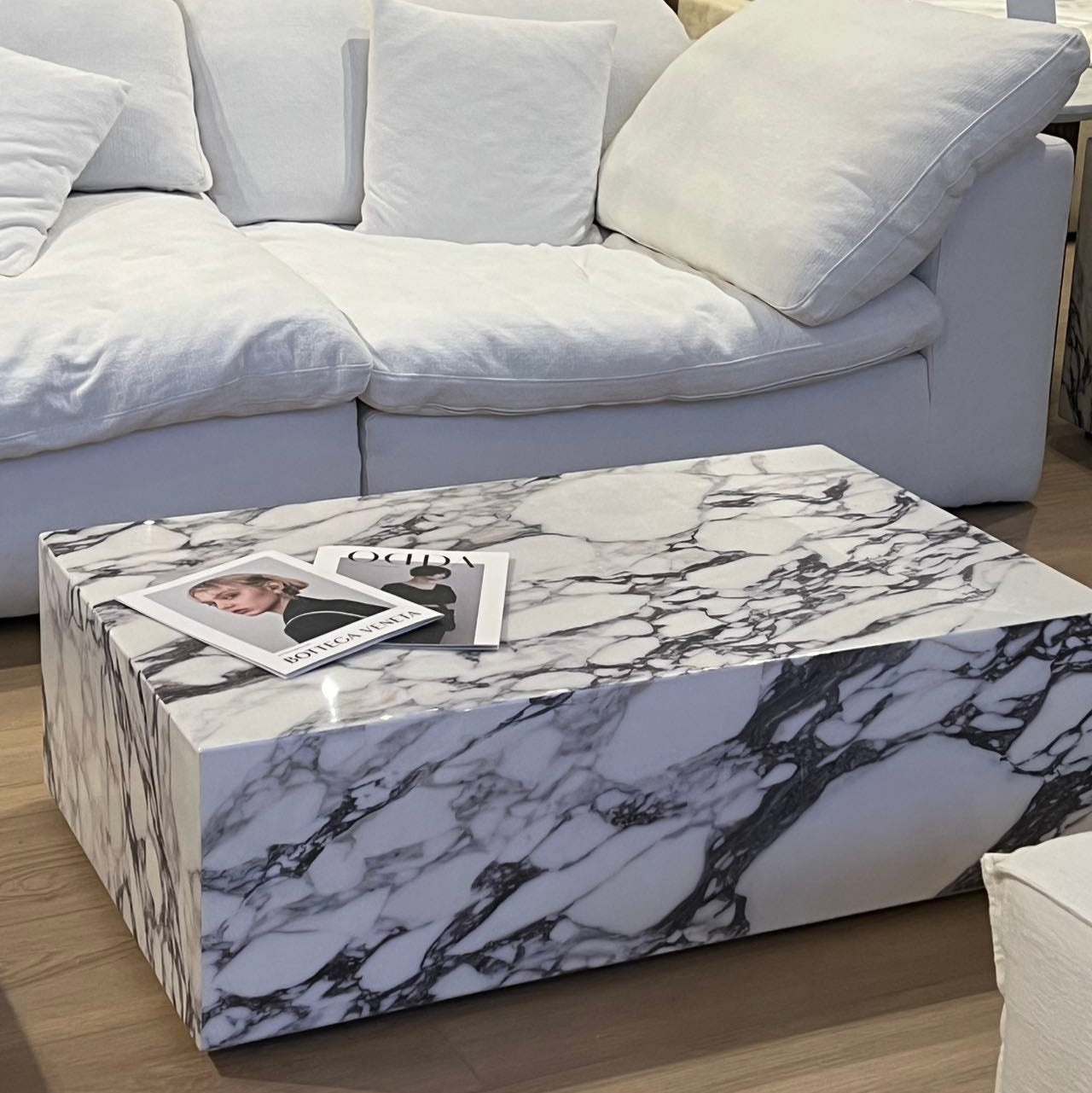 Bulgari Charm Coffee Table in white marble with dark veining styled in modern living room beside white modular sofa