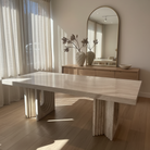 Caden Natural Travertine Dining Table styled in a sunlit dining room with a wood sideboard and neutral decor accents
