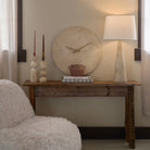 Caelo Candle Duo displayed on rustic console table with travertine clock and lamp, creating a warm and modern neutral decor setup