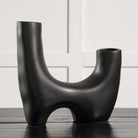 Caldera Vase in matte black finish displayed on table against white wall panel backdrop