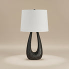 Calla Table Lamp with sculpted black wood base and white fabric shade in a neutral studio setting