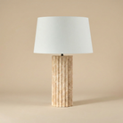 Table lamp with a textured wooden base and white shade on a beige background