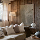 Callisto Travertine Table Lamp with fluted stone base and cream shade placed beside a cozy neutral sofa in rustic living room
