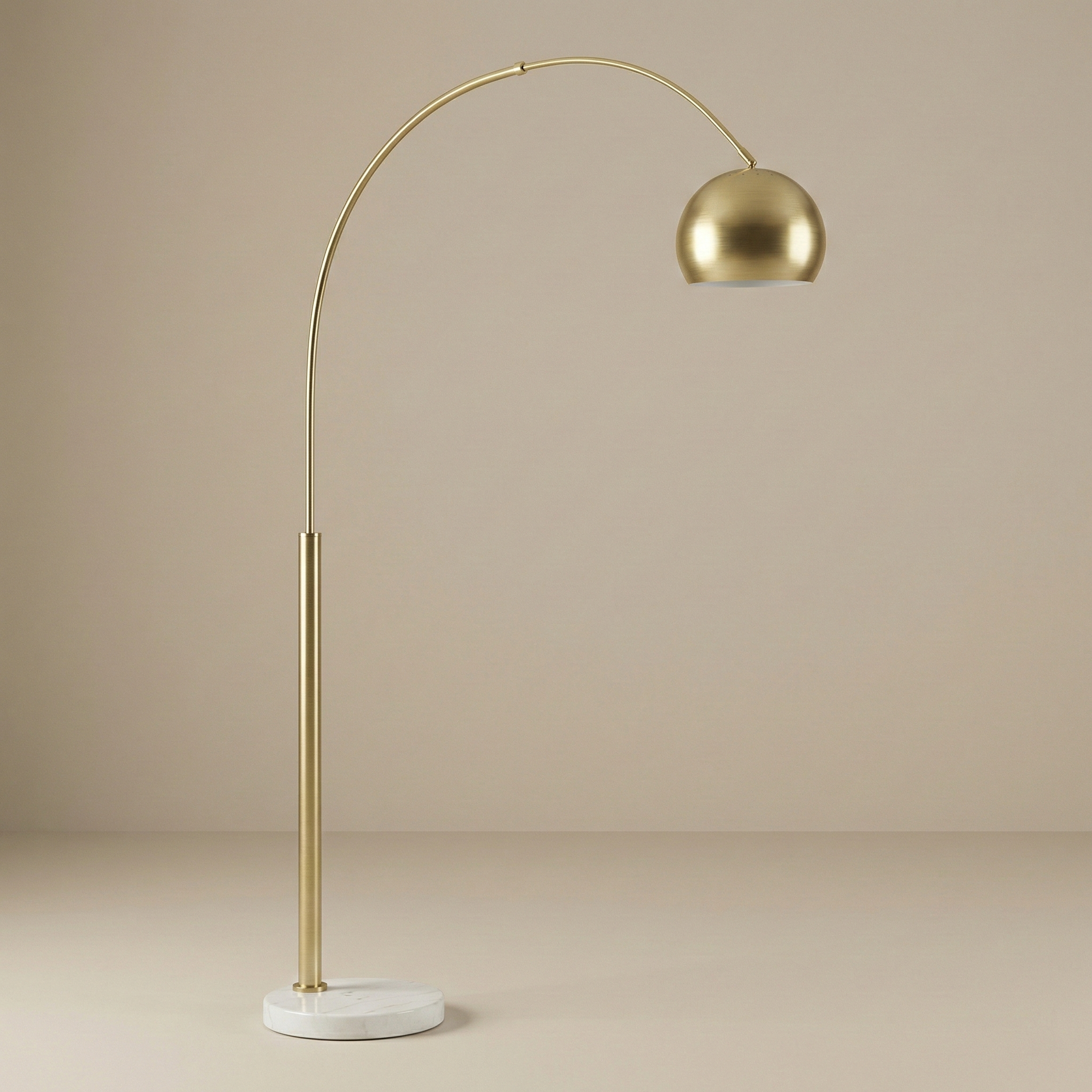 Studio view of the Cassia gold arc floor lamp featuring a curved metal stem and heavy white marble base.
