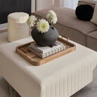 Cavallo Wood Tray styled on beige ottoman with black vase, white flowers, and stacked books in modern living room