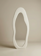 Cloud-shape full body mirror with an organic wavy white frame on a beige studio background.