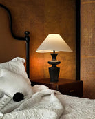 Contour Table Lamp with black sculpted base and white shade on bedside table in warm cozy bedroom