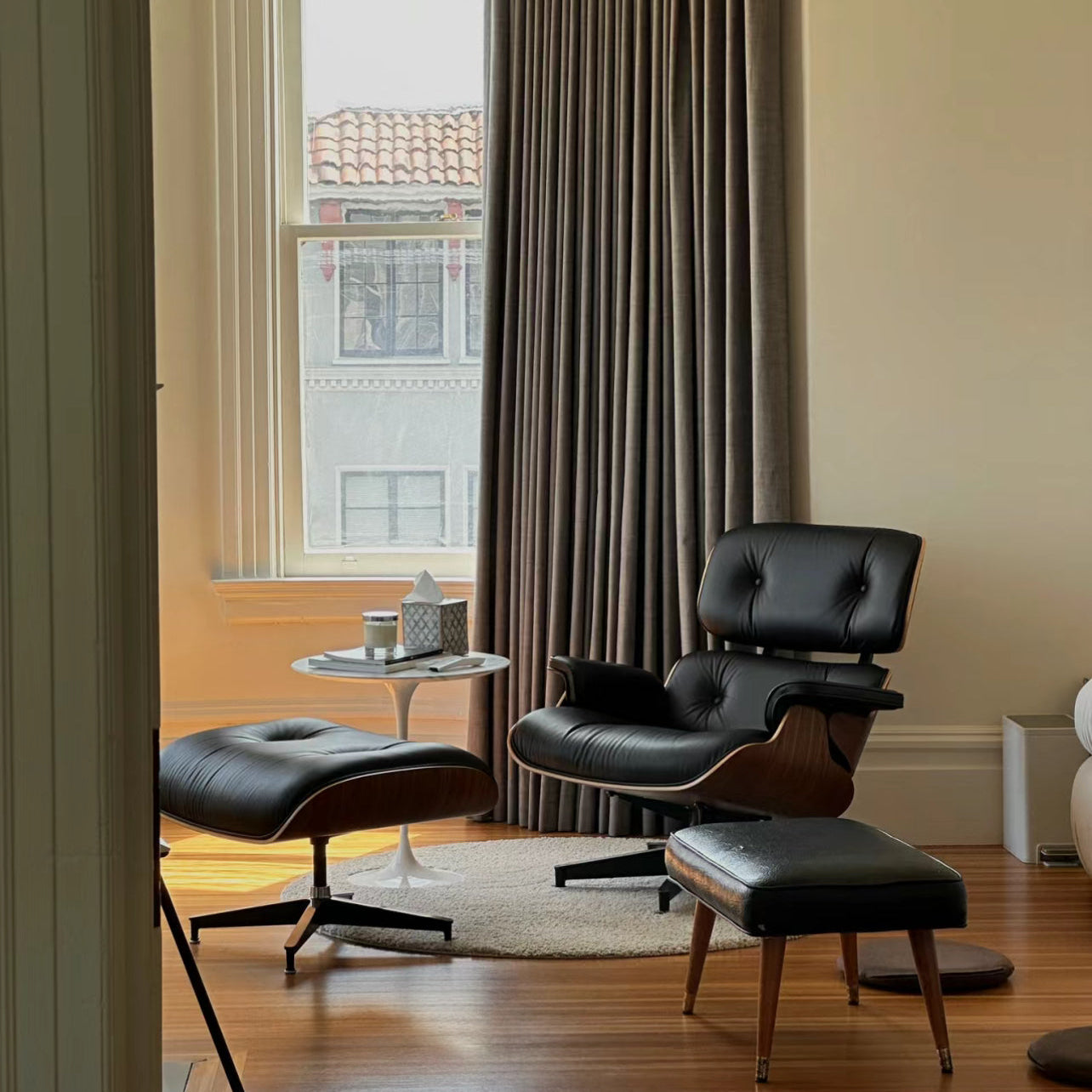 Eames Lounge Chair and ottoman in black leather with walnut frame styled by window in modern living room
