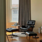 Eames Lounge Chair and ottoman in black leather with walnut frame styled by window in modern living room