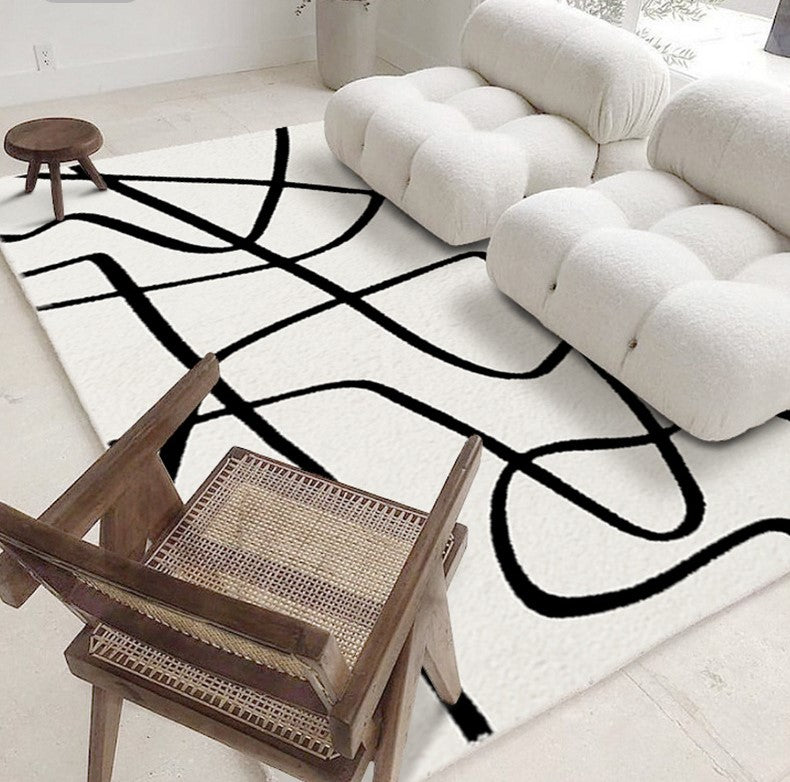 Eclipse Black and White Abstract Rug styled in a modern living room with white lounge chairs and a wooden accent chair