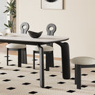 Side view of Eclipse Elegance dining table with sintered stone top and sculpted black wood legs paired with boucle dining chairs