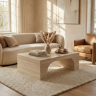 Modern living room with a beige sofa, travertine pattern arched coffee table, and decorative items.