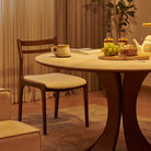 Elowen Round Dining Table with walnut base in warm evening light, styled with bread, grapes, and teapot