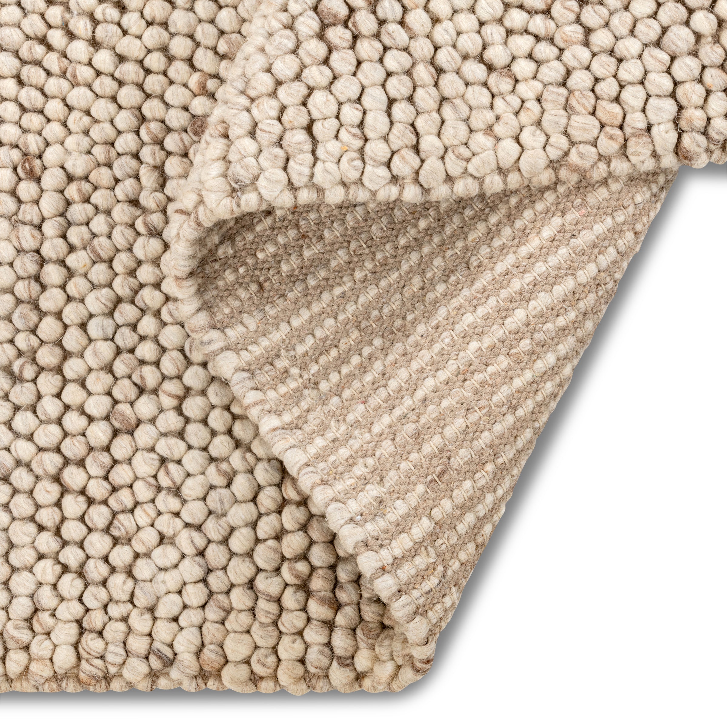 Folded corner of the beige Felix handmade textured rug, revealing its chunky pebble-like surface and durable backing.