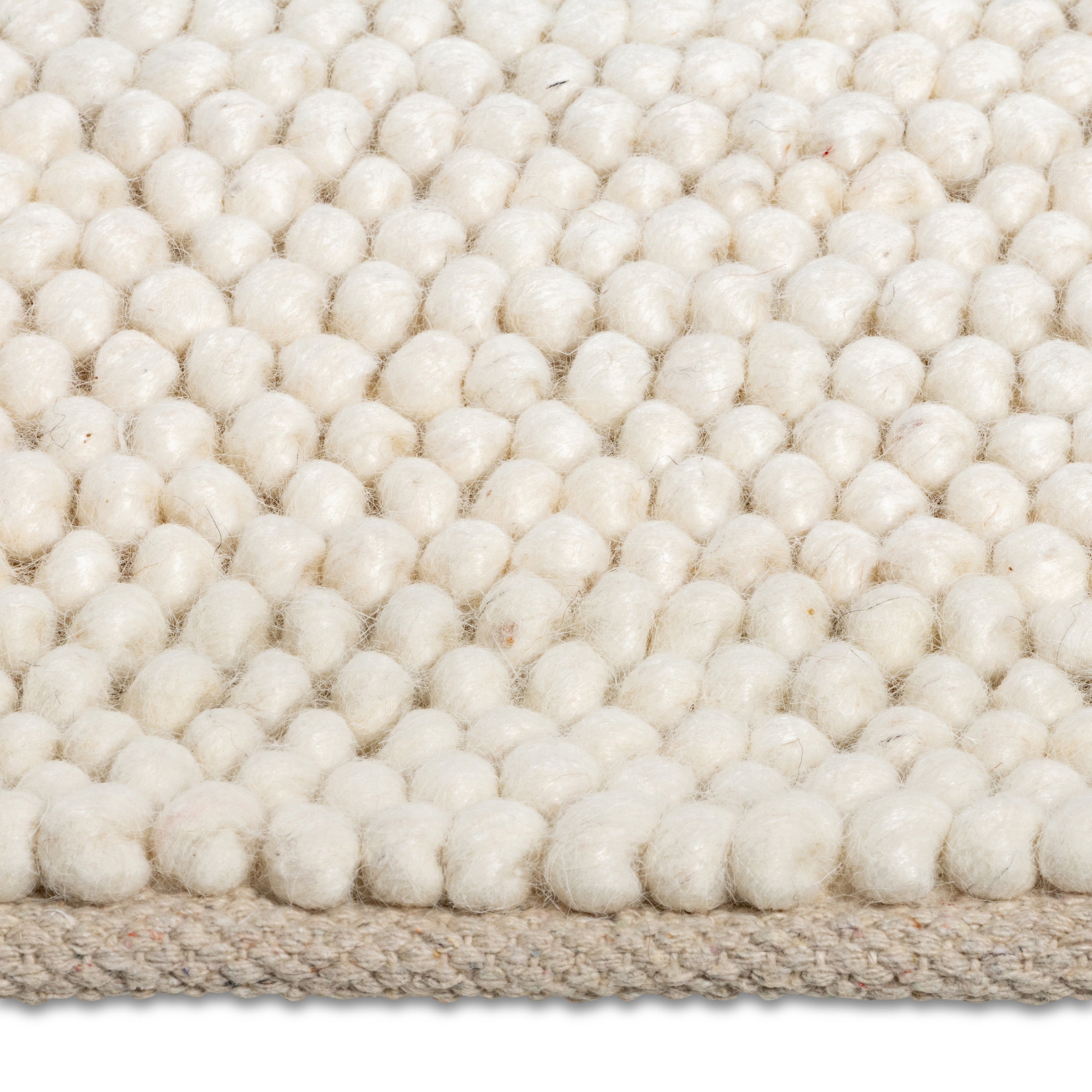 Macro close-up of the soft, pebble-like knotted texture of the cream Felix handmade rug.