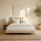 Neatly made bed with beige bedding in a bedroom setting.