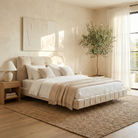 Floating platform bed styled in a bright modern bedroom, highlighting the recessed base that gives the chunky upholstered frame a hovering effect.