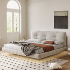 Floating Platform Bed Frame in beige fabric with tufted headboard and layered bedding in bright modern bedroom