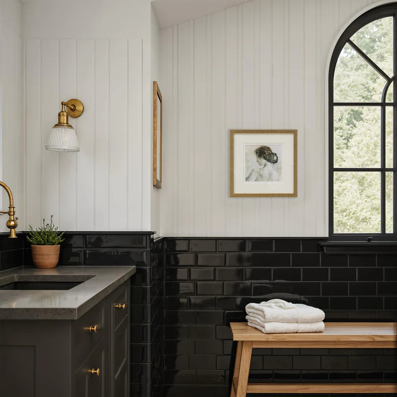The Florence framed portrait hanging on a white shiplap wall above black subway tile in a stylish, modern bathroom.